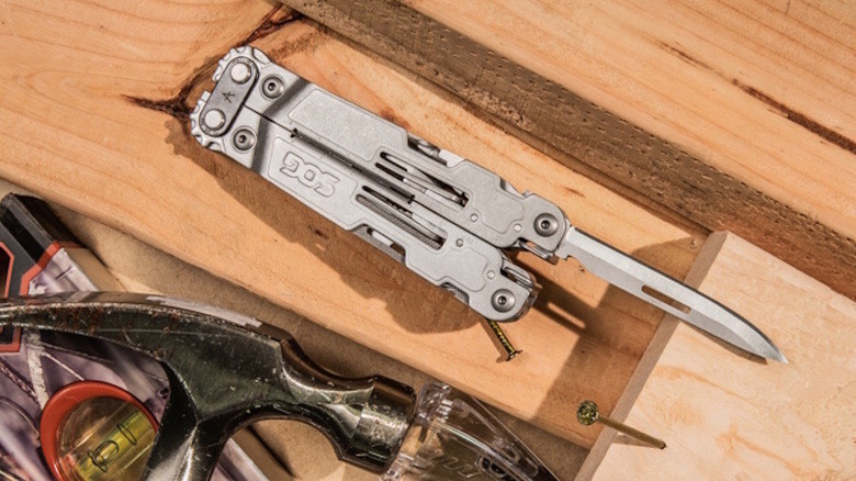 SOG PowerAccess Deluxe multitool sitting on top of wood with its knife out