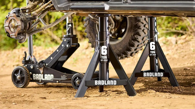 Two Badland jack stands holding up a vehicle on a dirt road.