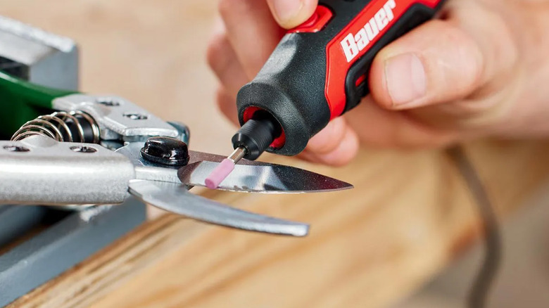 A person using a Bauer rotary tool to sharpen clippers.