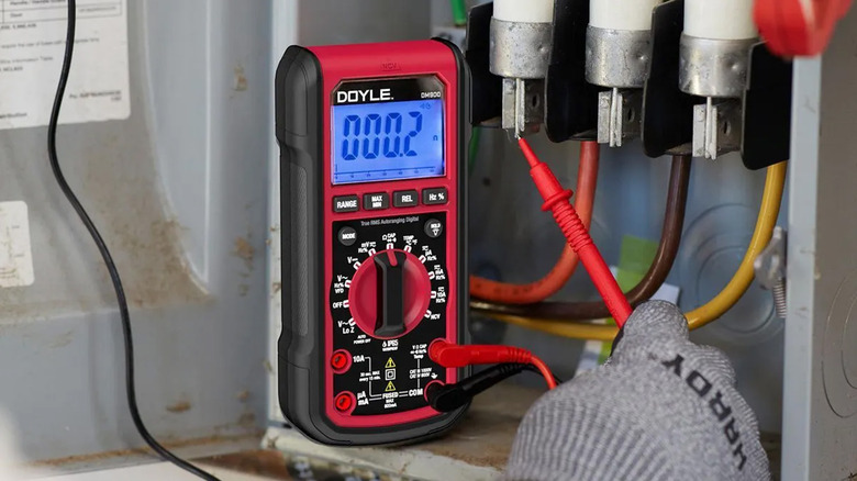 A technician using a Doyle multimeter to measure voltage.