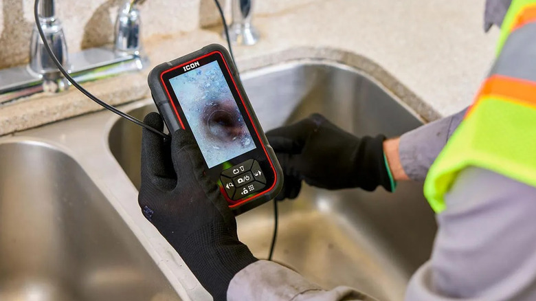 A plumber using an inspection camera to check in the drain of a sink.