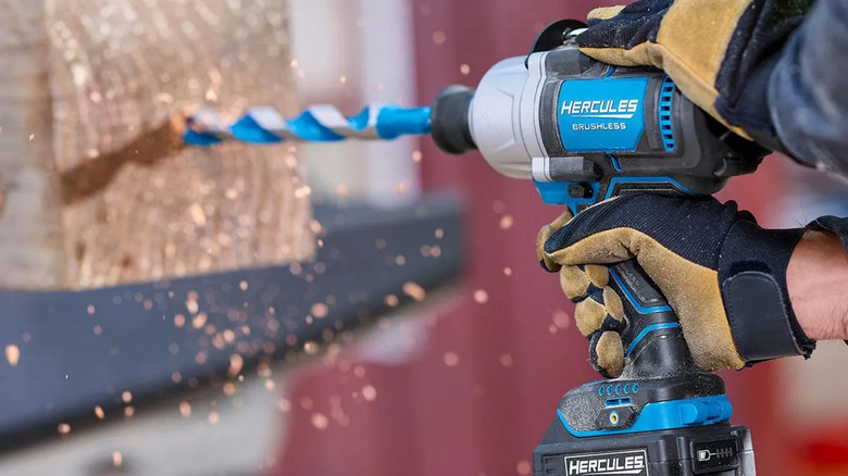 A worker using a Hercules drill to drill into a piece of wood.