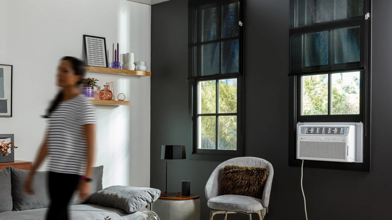 Room with a GE Profile AC unit in a window with a person moving away from the window