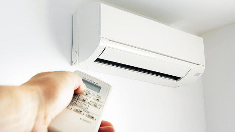 Hand pointing a remote at a mini split air conditioner