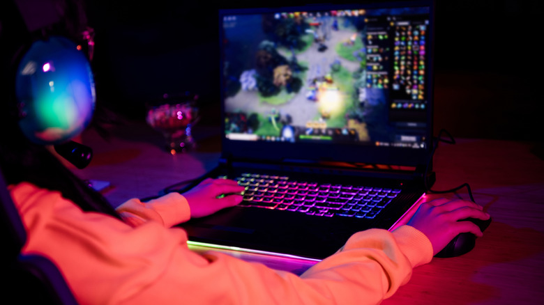 A person playing a game on a laptop with a mouse attached to it