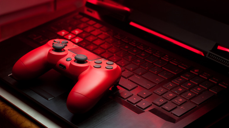 A red gamepad lying on a laptop, bathed in red light