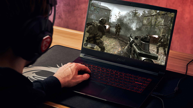 A person gaming on the MSI GF65 Thin laptop while wearing headphones