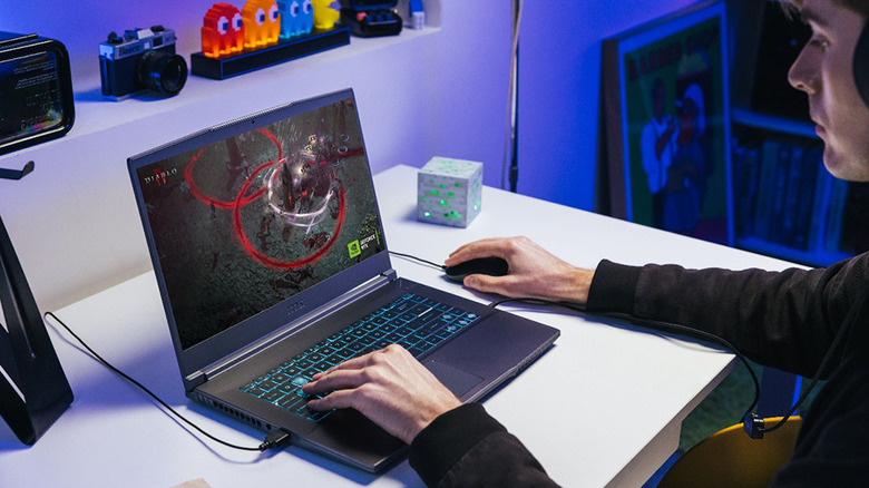 A person gaming on the MSI Thin 15 laptop while wearing headphones