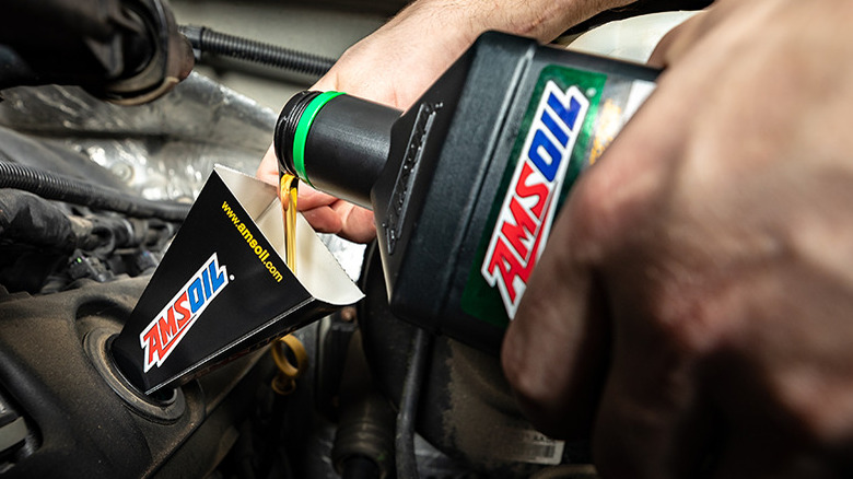 pouring AMSOIL oil in engine