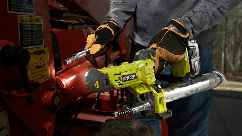 Close up of person using Ryobi grease gun