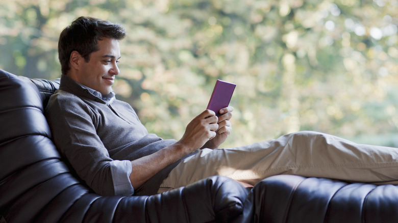 Man laying on couch reading an e-reader