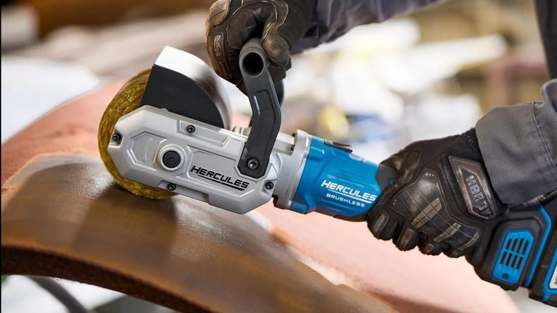 A worker using a Hercules surface conditioning tool on a piece of metal
