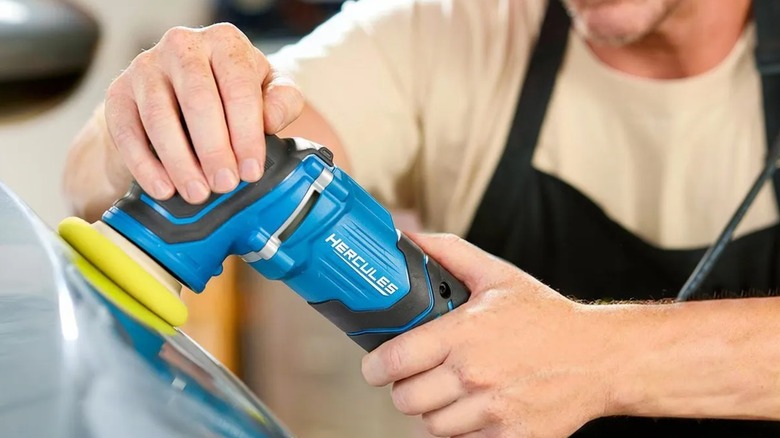 A worker buffing a car with a Hercules random orbit polisher