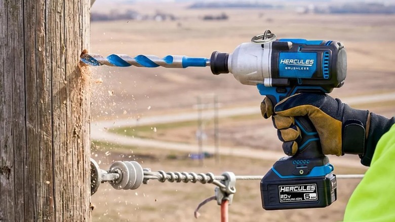 A worker drilling a hole in an electrical post with a Hercules impact wrench