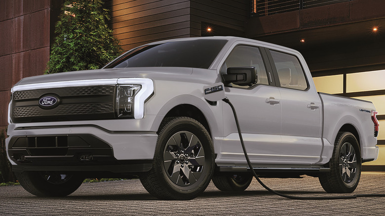 Light-colored Ford F-150 Lightning plugged into a charger