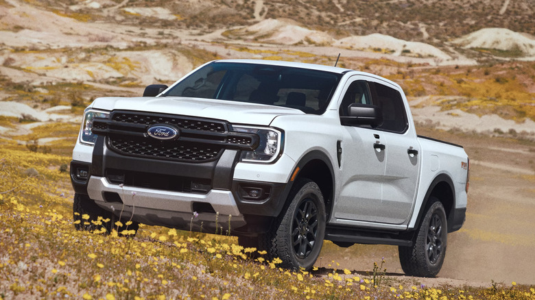 White 2026 Ford Ranger Lariat driving on dirt and flowers