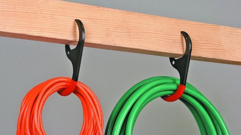 Set of two hooks attached to a wooden beam holding colored rope coils