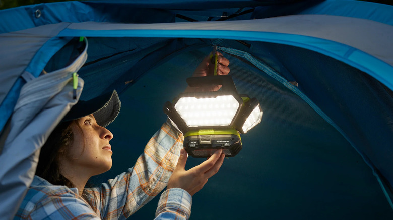 Person hanging a Ryobi 360 light from a tent.