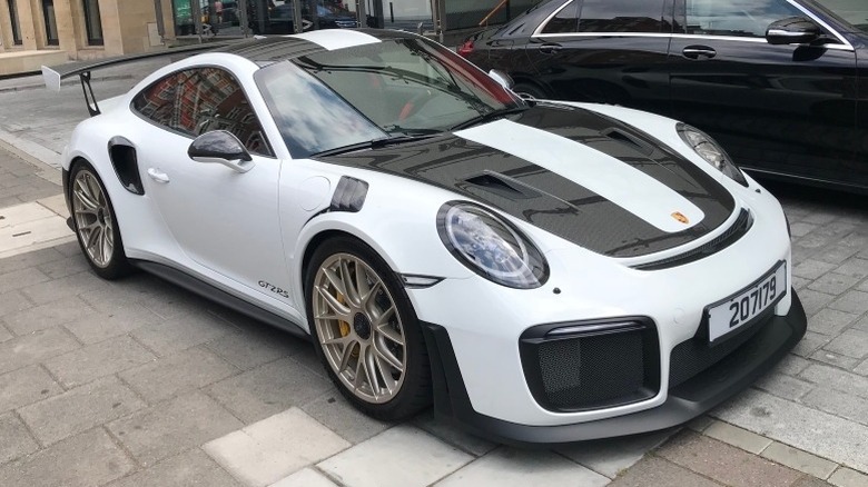 White Porsche GT2 RS parked on pavement next to a black car