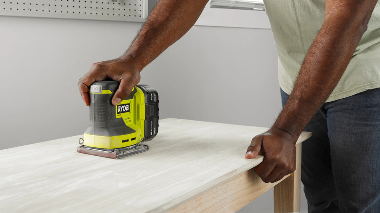 Ryobi 1/4 Sheet Sander being used to polish down lumber