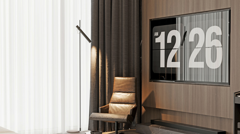Wall-mounted TV, black soundbar, leather chair, and floor-to-ceiling dark drapes in a luxurious living room.