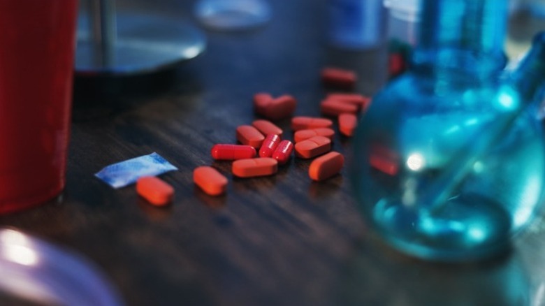 red pills on a table with a bong