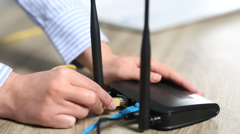 Man plugging in Wi-Fi router