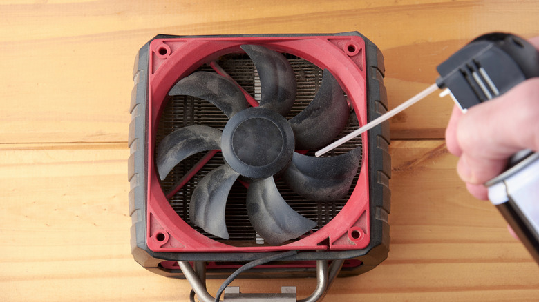 Spraying compressed air into a dusty computer fan.