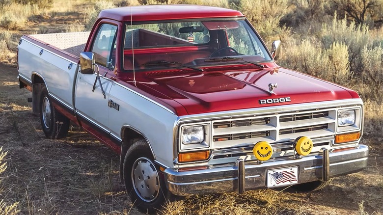 A two-tone red-and-white Dodge Ram sitting out in the high desert brush in a wide-open landscape with its KC Daylighter fog lights mounted up front.