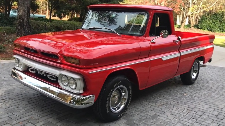 A beautifully restored candy-red 1965 GMC C/K 1500 Series C 10 sits gleaming on a brick driveway, while showing off every of its chrome piece.