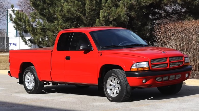 A bright red Dodge Dakota Club Cab in a clean driver-quality condition posing in a parking lot, looking tidy and remarkably rust-free for its age.