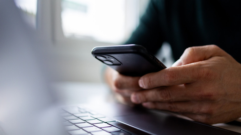 person holding iPhone in front of computer