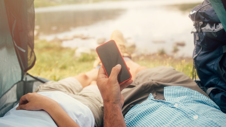 Man holding smartphone while camping