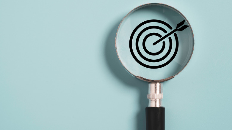 Magnifying glass over a target on a blue wall