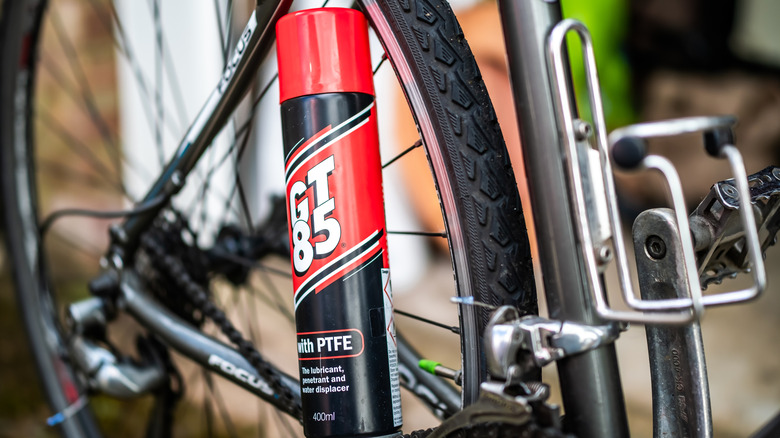 A close up shot of GT85 can with a bicycle in the background