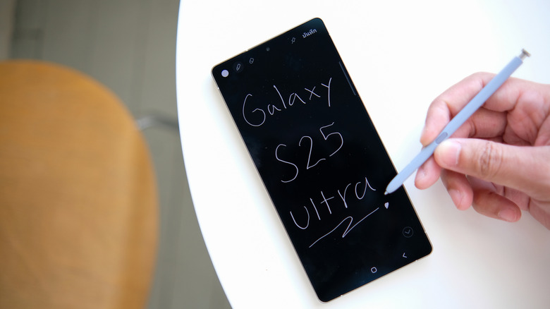A person writing on a Samsung S25 ultra phone with the included S-pen, finished here in purple.