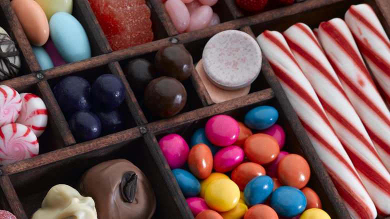 An arrangement of colorful candy in a wooden box, sorted into individual trays