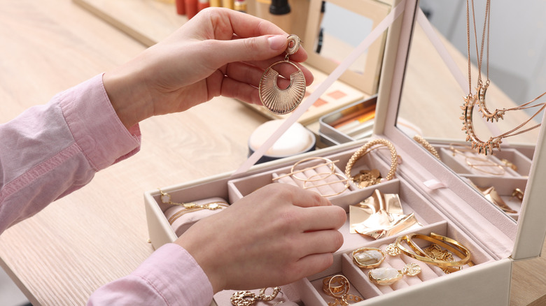 Woman holding an earring while looking through a jewelry box