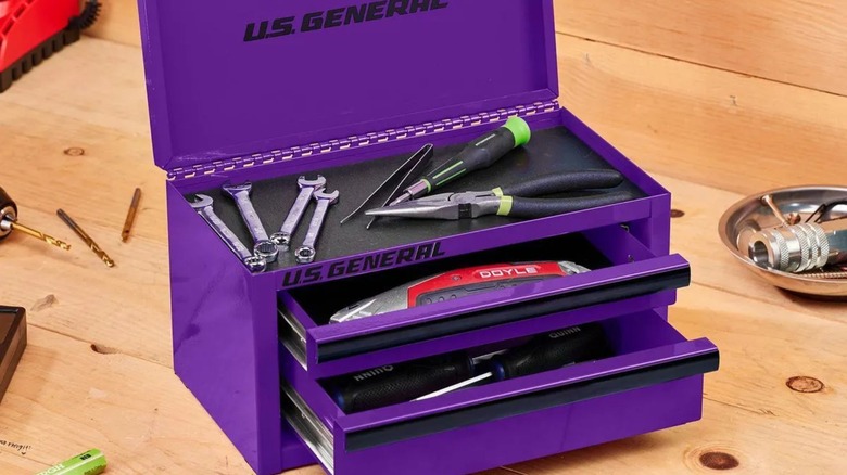 Harbor Freight's U.S. General mini toolbox in purple, set atop a wooden work surface