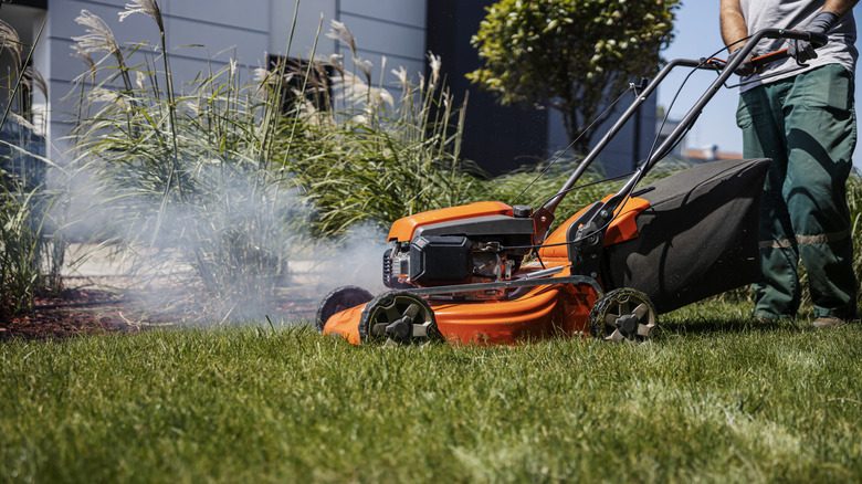 cutting grass with a lawn mower that's smoking