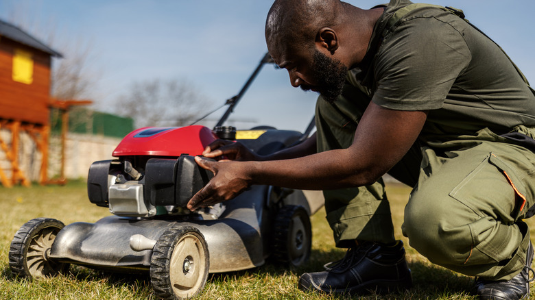 man inspecting his lawn mower