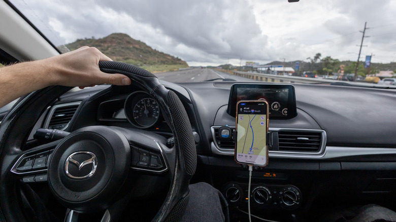 Interior view of Mazda3 showing person driving with phone showing GPS route