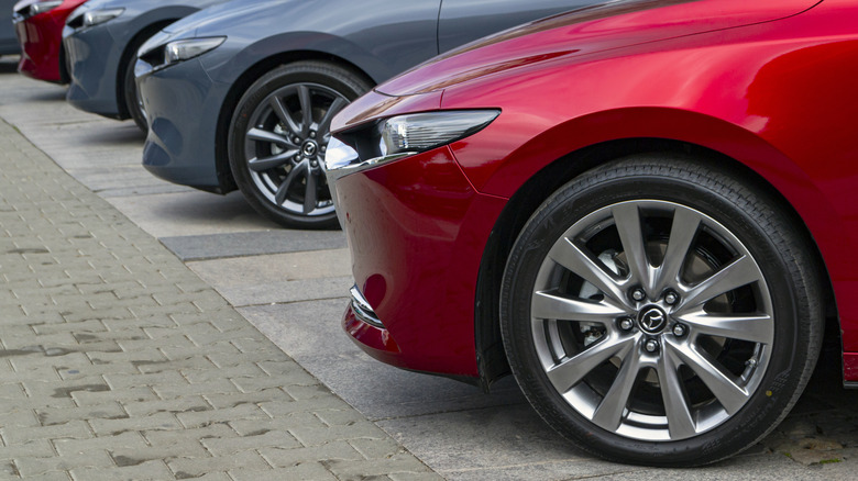 View of front halves of a row of Mazda3 cars parked on concrete