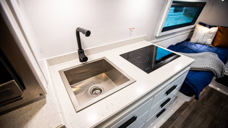 Interior of an Oliver Apex X23 travel trailer showing the sink and induction cooktop