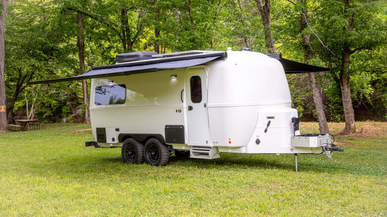 White Oliver Travel Trailer with two awnings out parked on grass