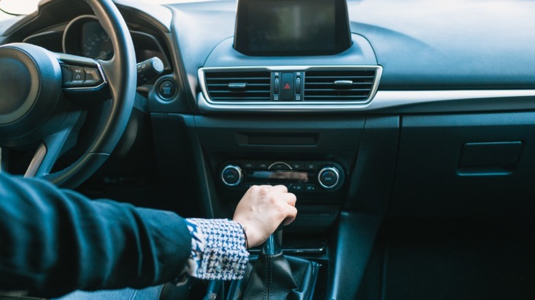 back view of driver keeping his hands on the manual transmisson