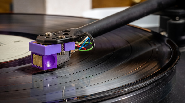Close-up of a purple turntable cartridge playing a vinyl record.