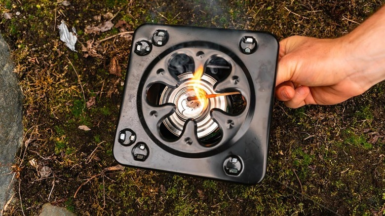 Using a matchstick to light a fire in a portable camp stove.