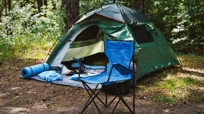 A camping chair and tent placed outdoors.
