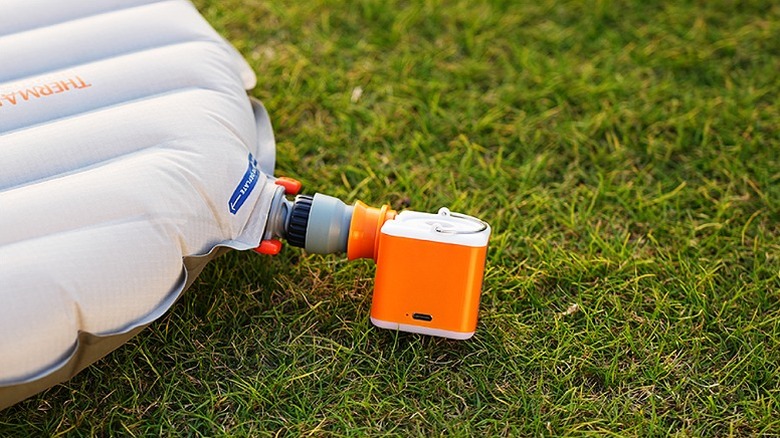 A tiny air pump inflating an object placed on a grass.